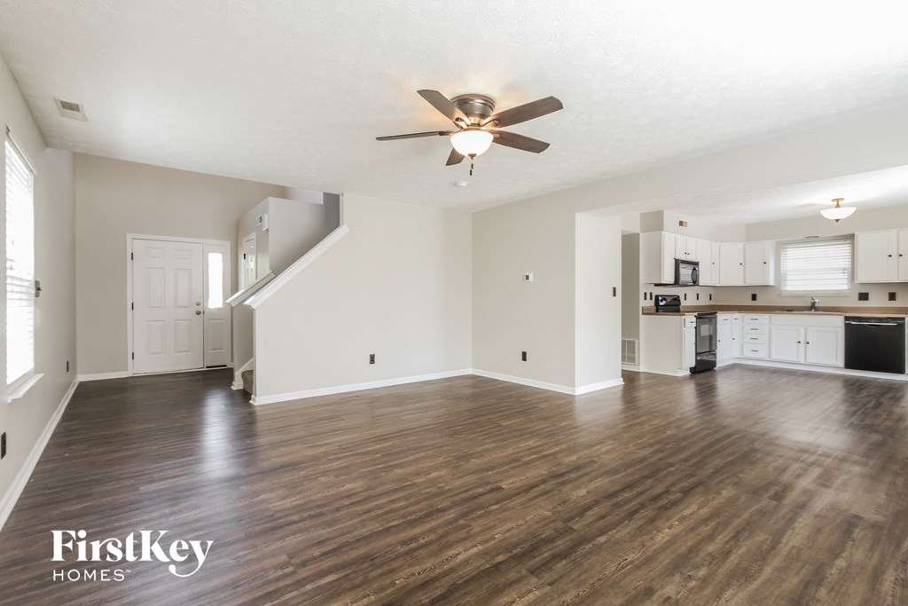 an empty living room and kitchen with a ceiling fan