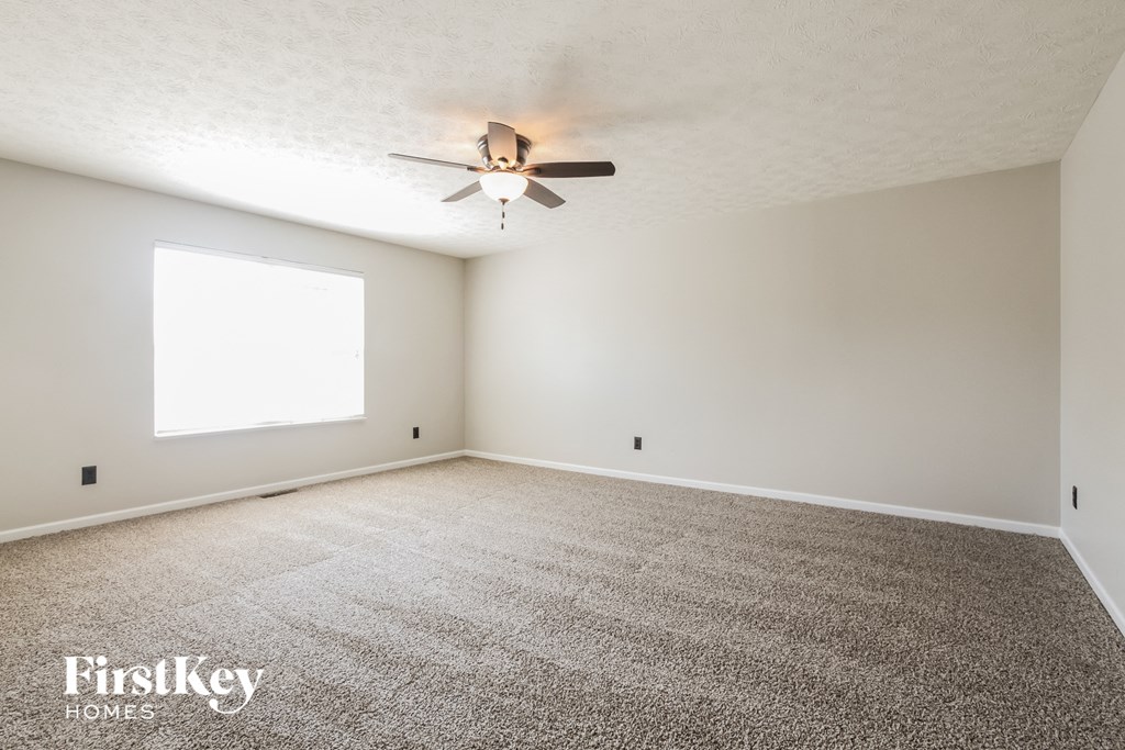 an empty living room with a ceiling fan and a window