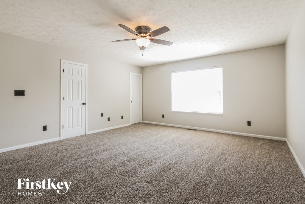 an empty living room with a ceiling fan and a window