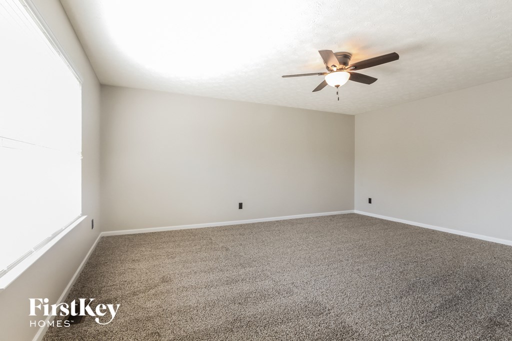 an empty living room with a ceiling fan and a carpet