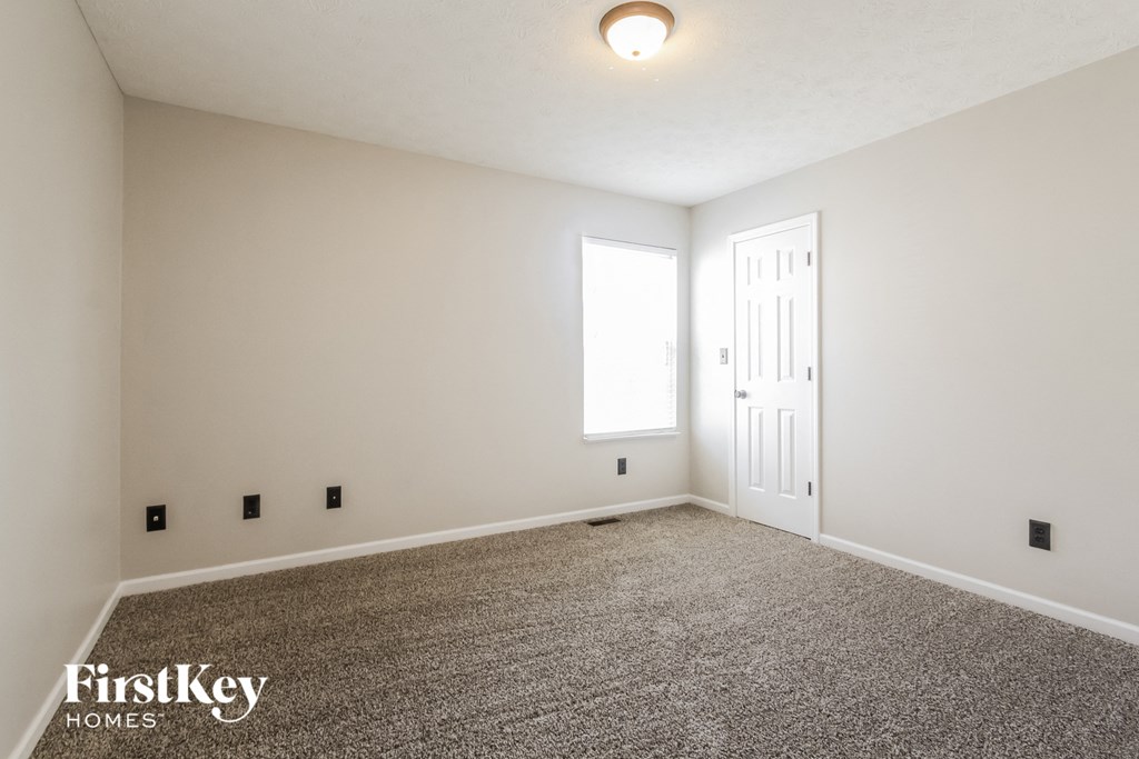 a spacious living room with carpet and white walls