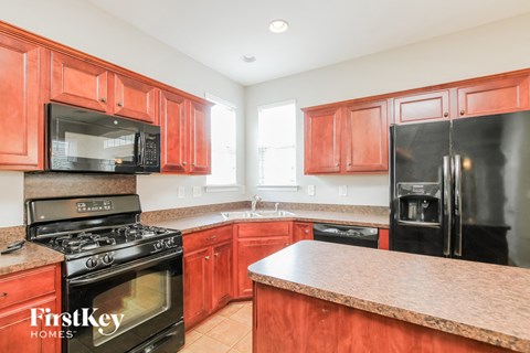 A kitchen with red cabinets and black appliances.