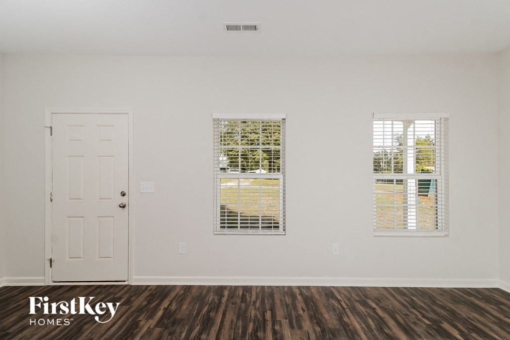 the living room of a home with a white door and two windows