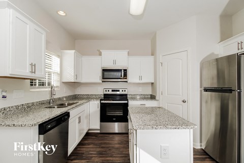 a kitchen with white cabinets and granite counter tops and stainless steel appliances
