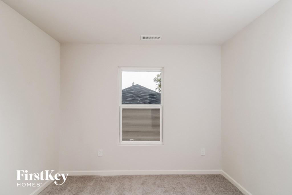 a bedroom with white walls and a window with a window shade