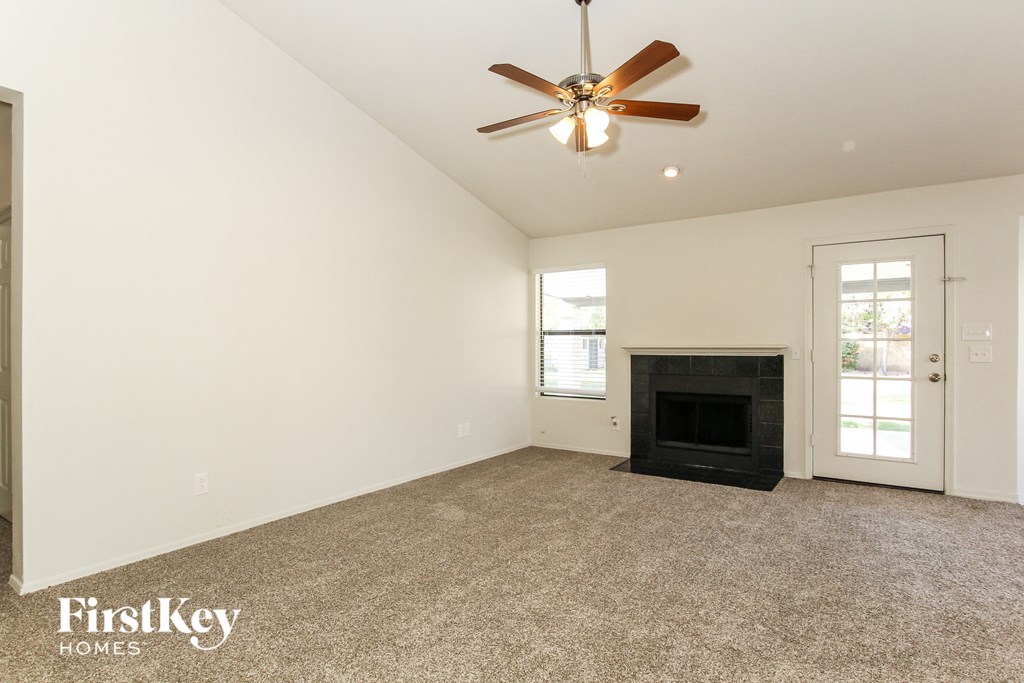 the living room has a fireplace and a ceiling fan