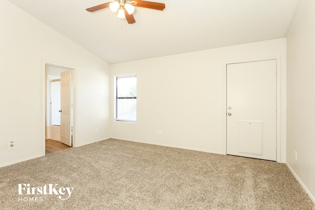 a bedroom with white walls and carpet and a ceiling fan