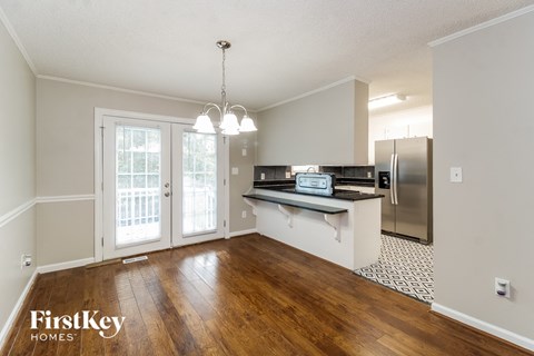 A kitchen with wooden floors and a stainless steel refrigerator.