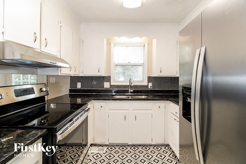A kitchen with a stainless steel refrigerator and black countertops.