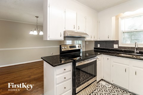 A kitchen with white cabinets and black countertops.
