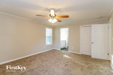 A spacious room with a ceiling fan and two doors.