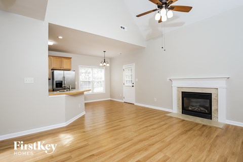 A spacious living room with a fireplace and a ceiling fan.