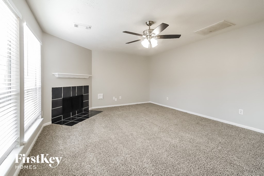 A spacious room with a fireplace and a ceiling fan.