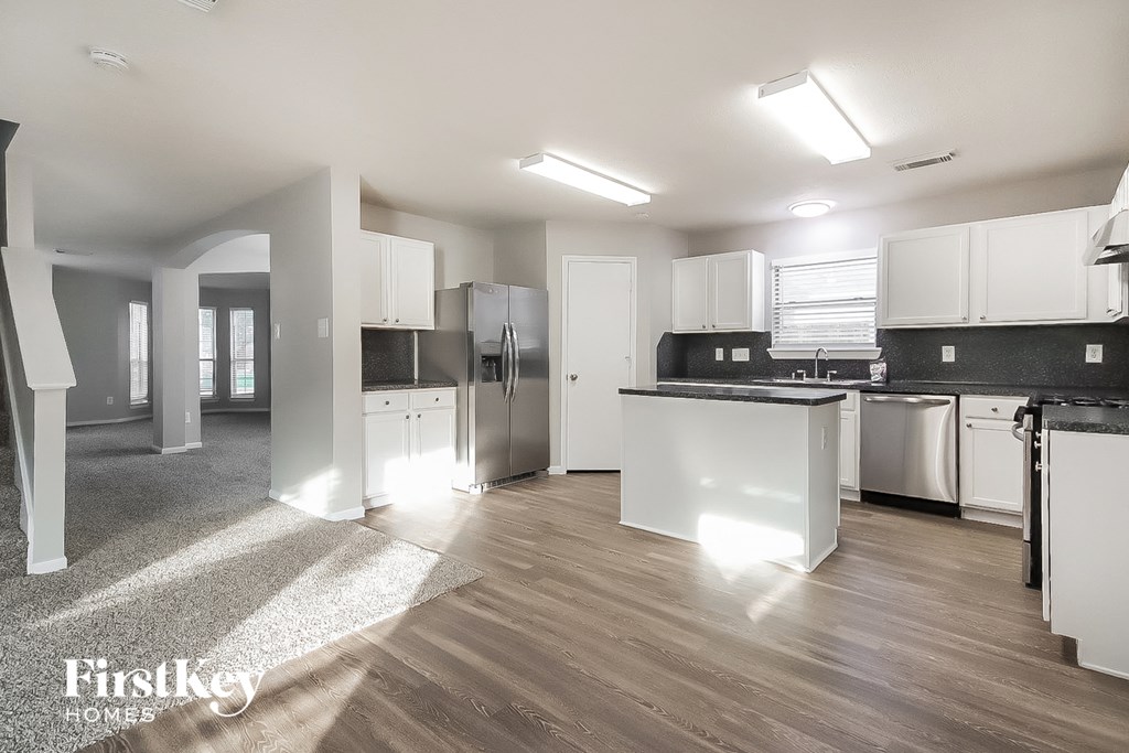 A modern kitchen with wooden floors and white appliances.