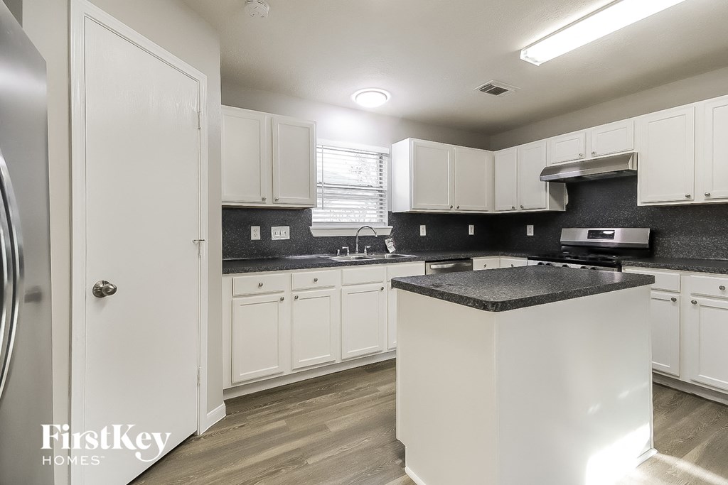 A kitchen with white cabinets and a black countertop.