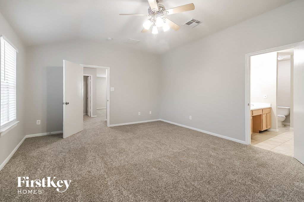A spacious room with a carpeted floor and a ceiling fan.
