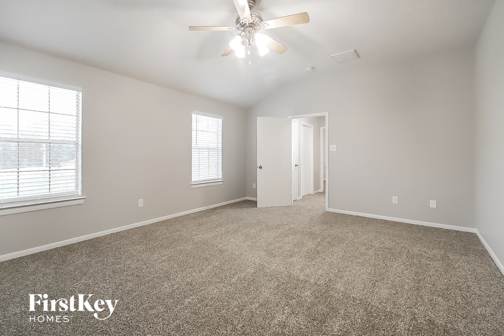 A spacious room with a ceiling fan and carpeted floor.