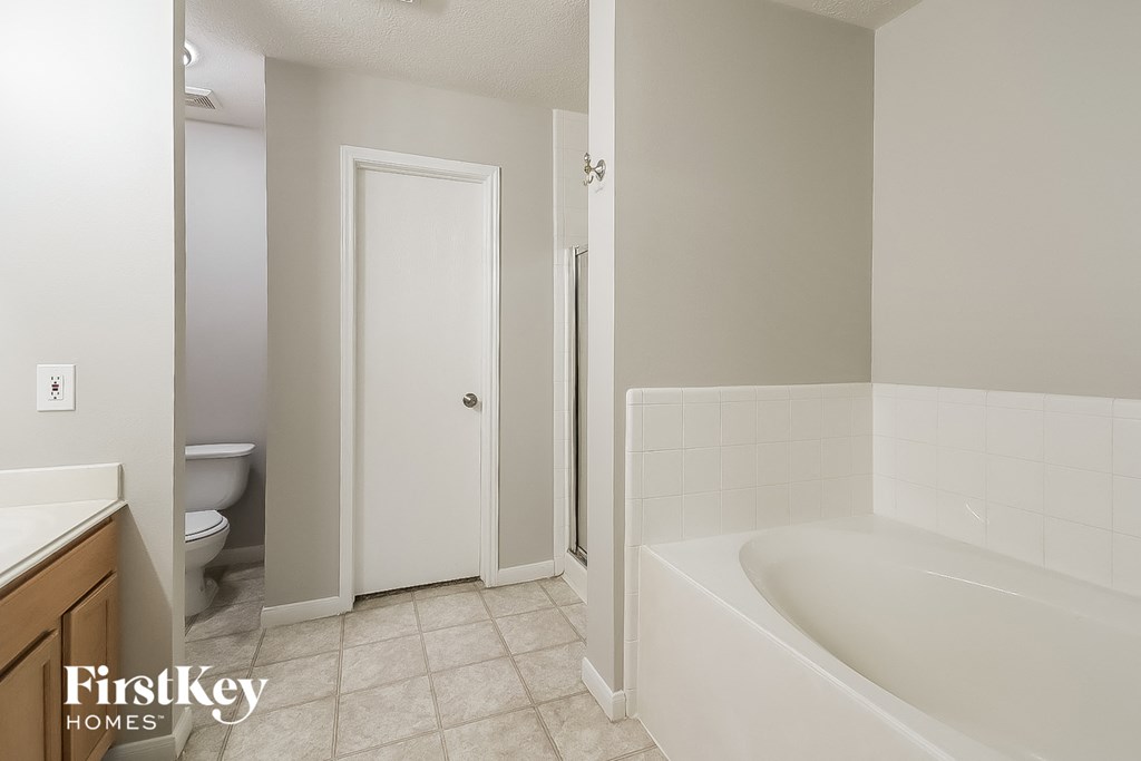 A white bathroom with a tub and toilet.