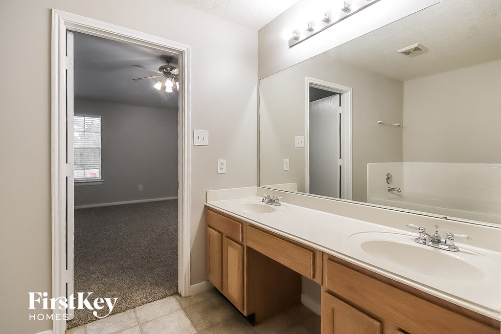 A bathroom with a sink, mirror, and a fan.