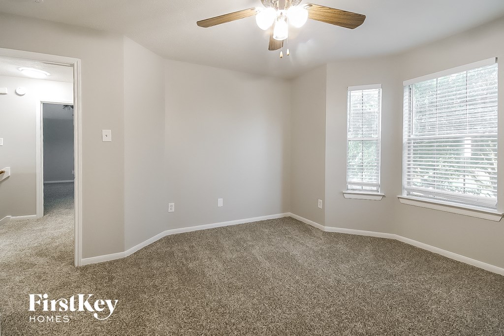 A room with a carpeted floor and a ceiling fan.