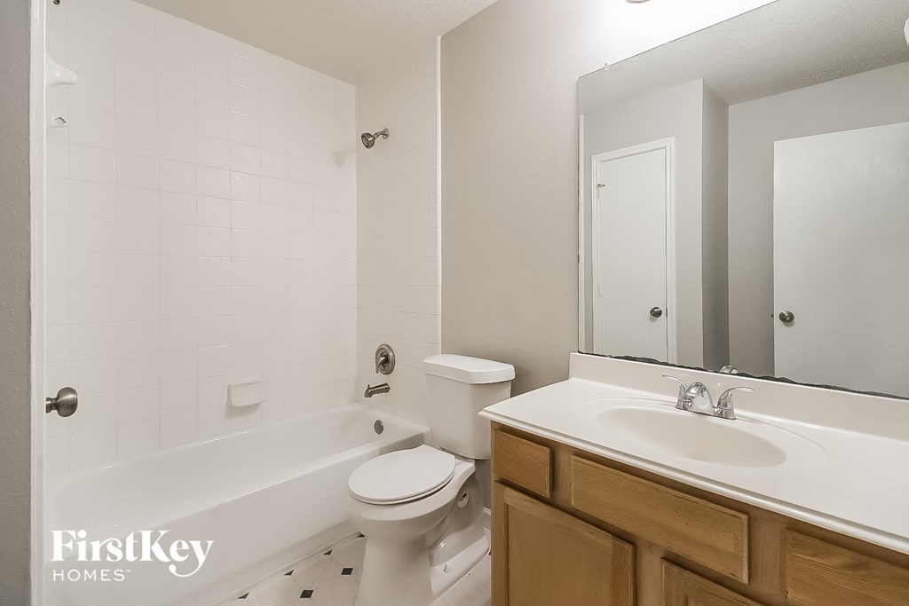 A white bathroom with a toilet, sink, and mirror.