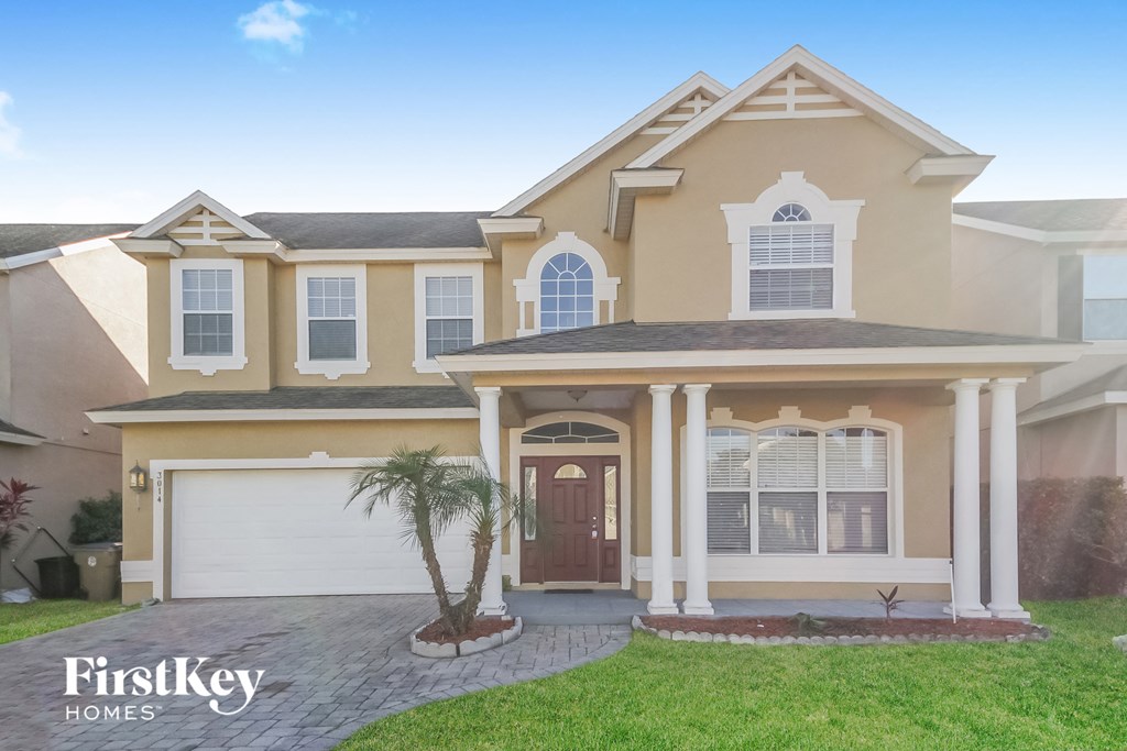 A house with a brown and beige exterior and a palm tree in front.