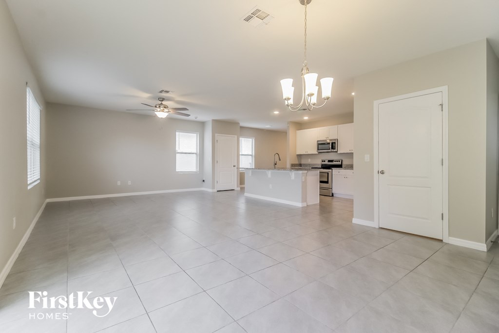 A spacious, empty room with a kitchen area in the background.