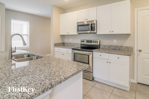 A kitchen with granite countertops and white cabinets.