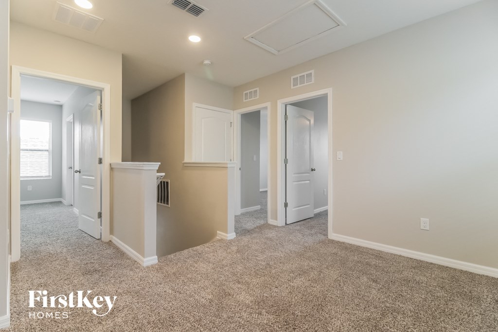 A carpeted room with a white door and a FirstKey HOMES logo.