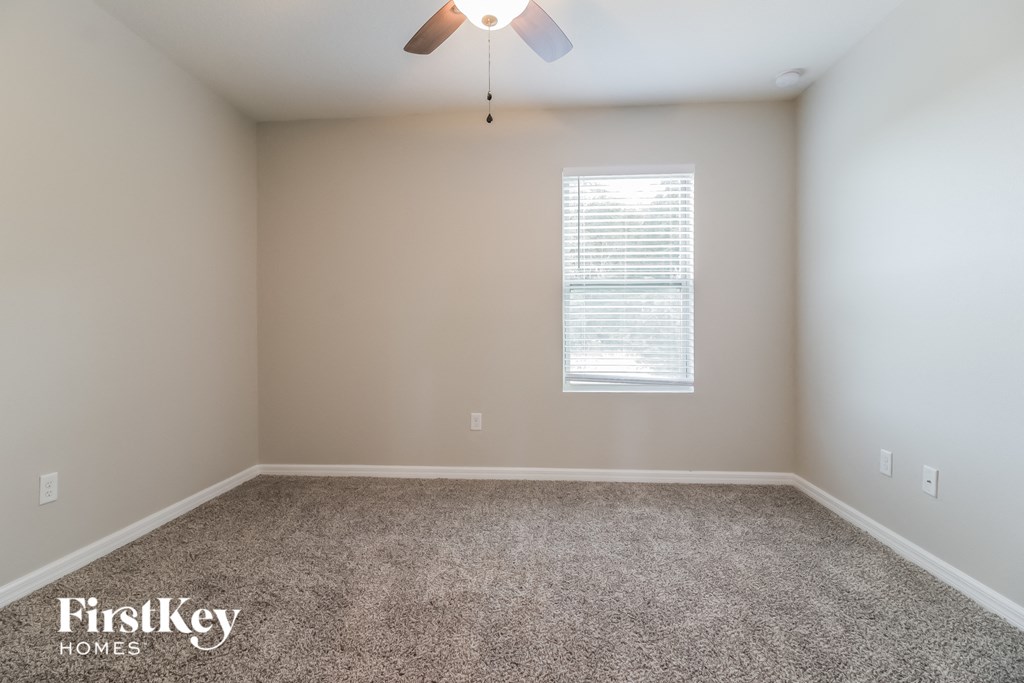 A room with a carpet floor and a ceiling fan.