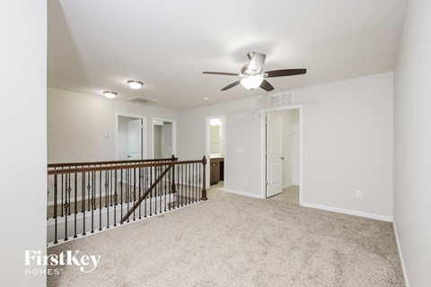 a spacious living room with carpet and a ceiling fan