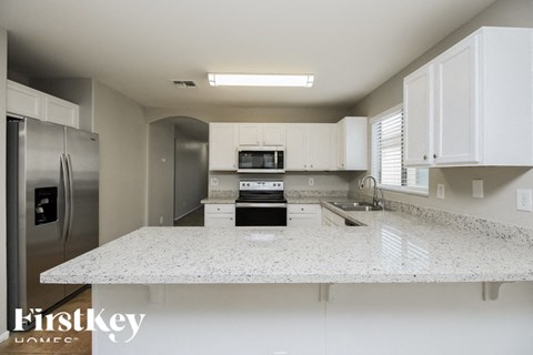 A kitchen with a granite countertop and stainless steel appliances.