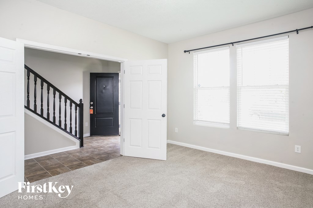 a living room with a staircase and a white door and windows