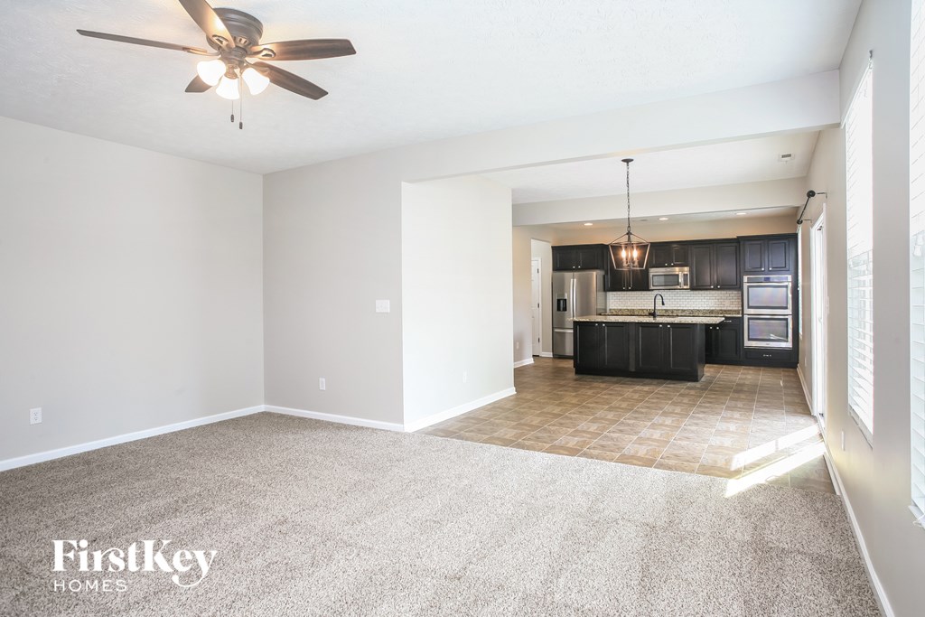 an empty living room and kitchen with a ceiling fan
