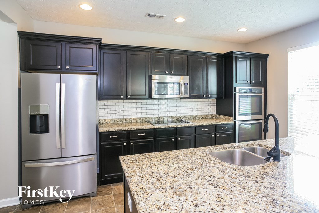 a kitchen with black cabinets and granite counter tops and stainless steel appliances