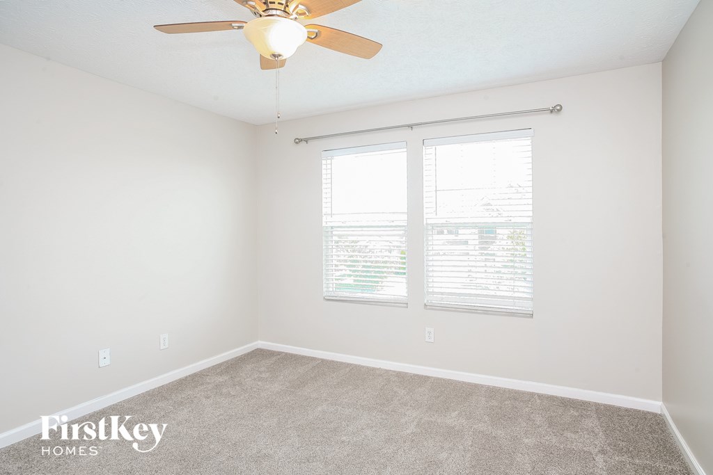 a bedroom with two windows and a ceiling fan