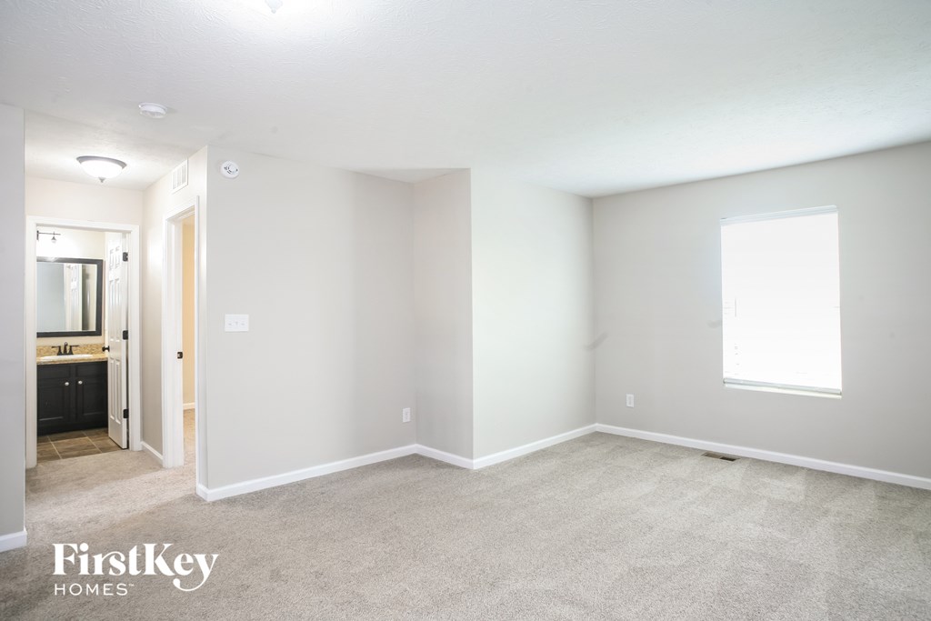 the living room of an apartment with carpet and a bathroom