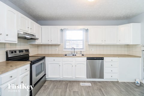 a white kitchen with white cabinets and stainless steel appliances