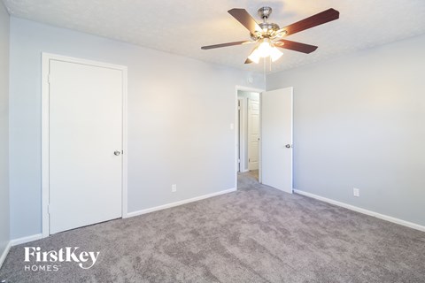 a bedroom with white walls and a ceiling fan