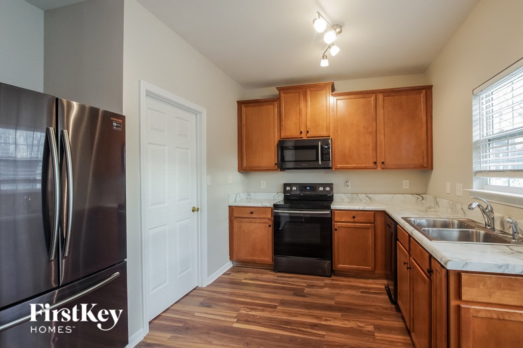 an empty kitchen with wooden cabinets and a stainless steel refrigerator