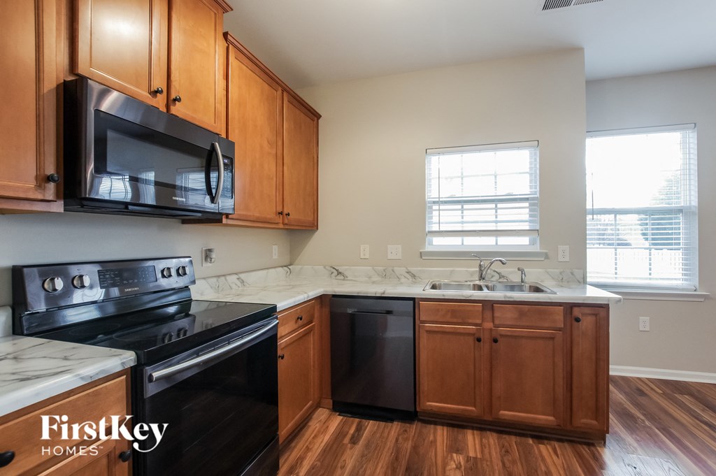an empty kitchen with wooden cabinets and a black stove and microwave