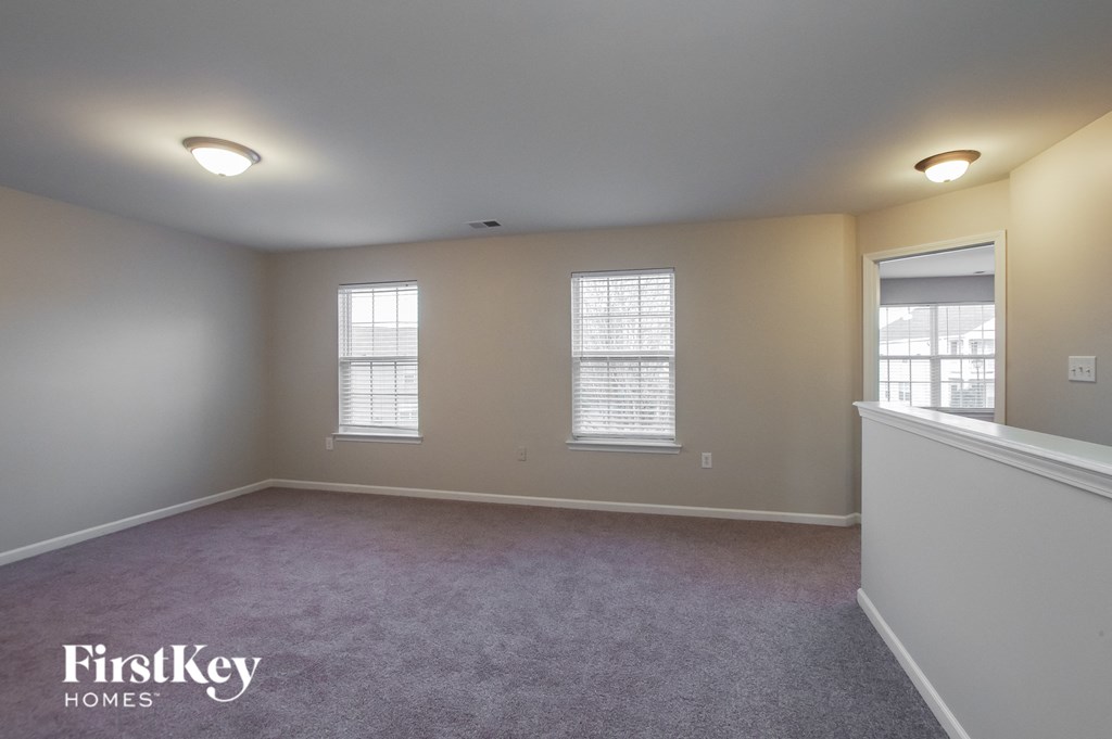 a bedroom with a carpeted floor and three windows