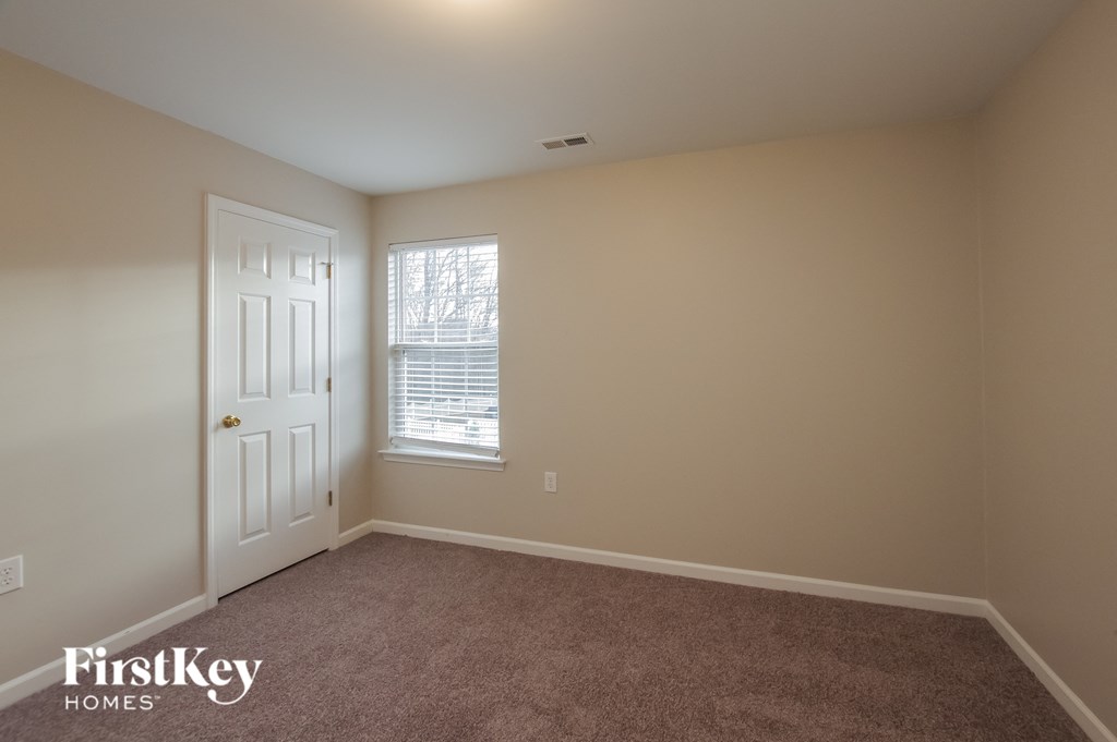 a bedroom with a carpeted floor and a white door and window