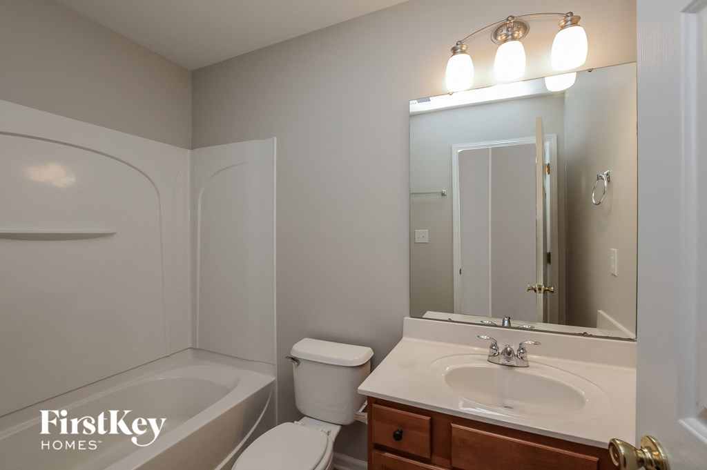 a bathroom with a sink toilet and mirror and a bath tub