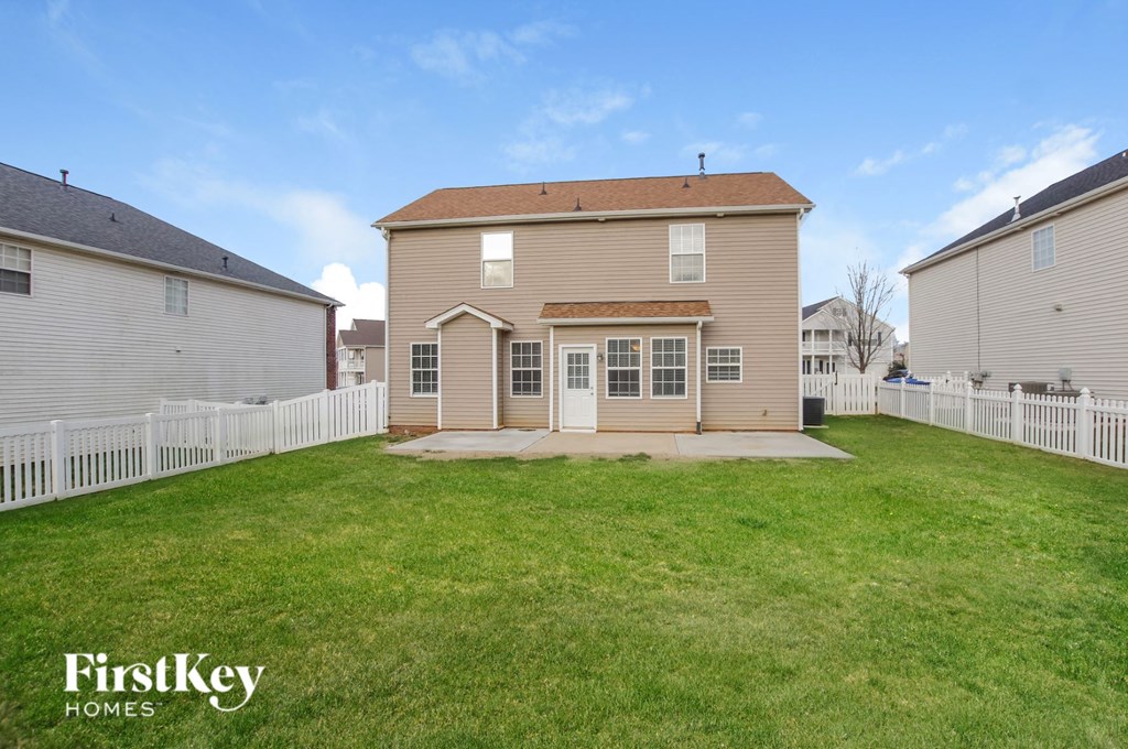 the back of a house with a yard and a white fence