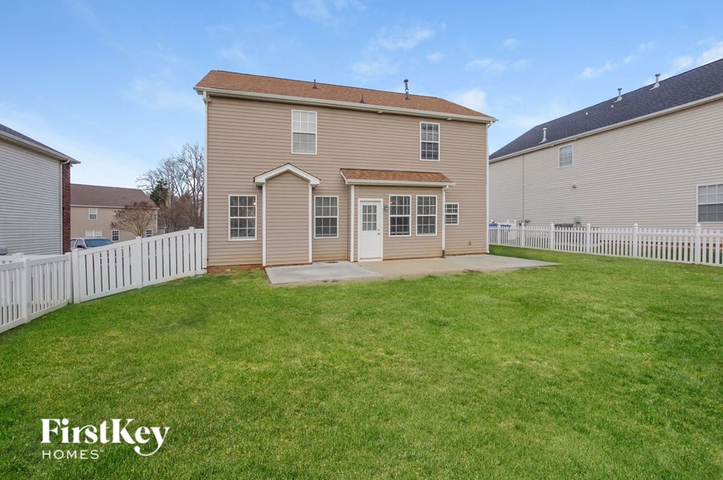 the backyard of a house with a yard and a white fence
