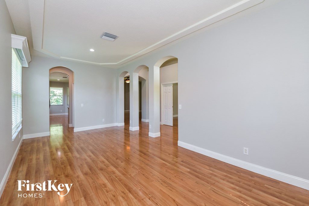 A spacious room with wooden floors and arched doorways.