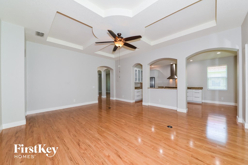 A spacious room with wooden floors and a ceiling fan.