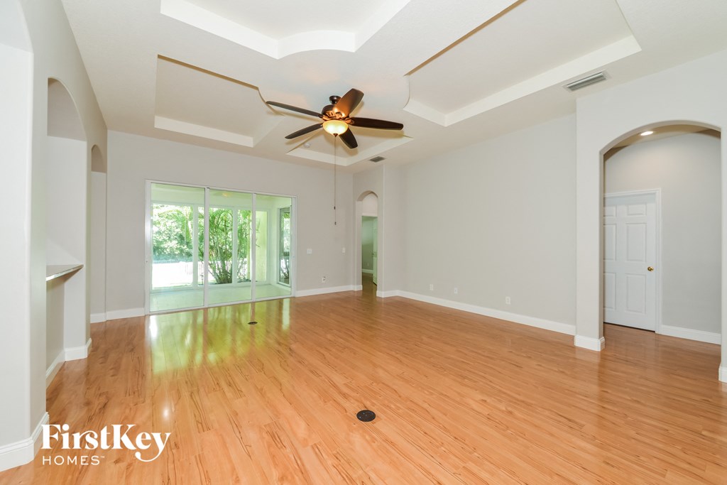 A spacious room with wooden floors and a ceiling fan.