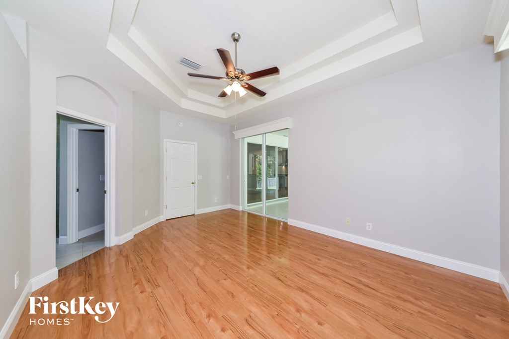 A spacious room with wooden floors and a ceiling fan.